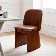 a brown leather chair sitting on top of a white rug next to a wooden table