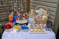 a table topped with cupcakes and cakes next to a basket filled with candy