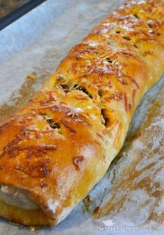 a long piece of bread sitting on top of a baking pan covered in melted cheese