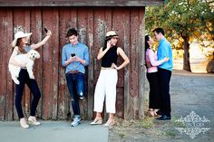 four people are standing in front of a barn and one person is holding a dog