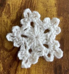 a crocheted snowflake sitting on top of a wooden table