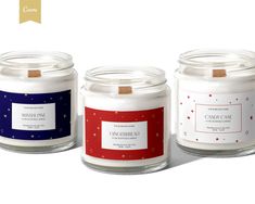 three candles with labels on them sitting side by side in front of a white background