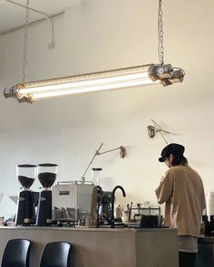 a man standing in front of a counter filled with coffee machines and cups on top of it