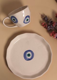 two white bowls with blue and green designs on them next to a vase filled with flowers