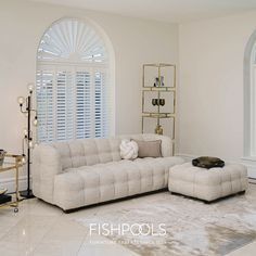 a living room filled with furniture next to a tall white window covered in shutters