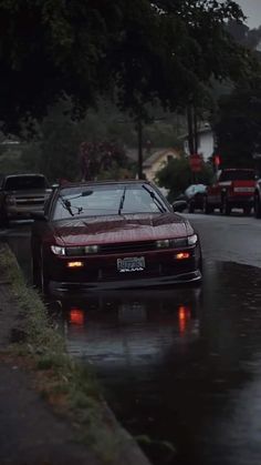 cars are parked on the side of the road as it rains and water comes down