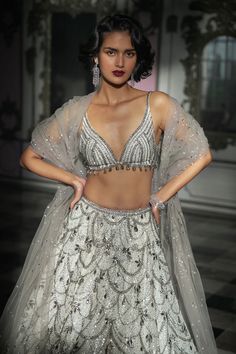 This lehenga set features grey crystal embroidery in chandelier inspired pattern on a white tonal sequin base. The matching blouse and dupatta have grey crystal drops..From Seema Gujral's Inara collection. DELIVERY TIMEPlease allow 8-12 weeks for your outfit to arrive. FABRIC DETAILSNet Professional cleaning only. Seema Gujral, Net Embroidery, Crystal Embroidery, Runway Outfits, White Chandelier, Lace Hem, Sequins Embroidery, 12 Weeks, Professional Cleaning