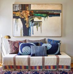 a large painting hangs above a couch with colorful pillows on it's back end