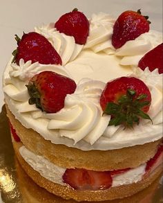 a cake with white frosting and strawberries is on a gold platter, ready to be eaten