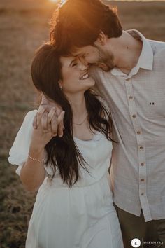 a man and woman kissing in an open field with the sun shining down on them