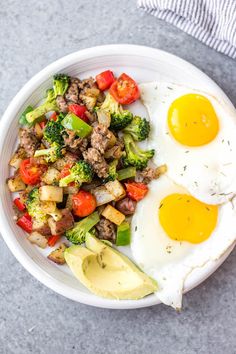 two fried eggs and vegetables in a white bowl