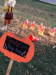 a yard sign with candy corn on it in front of some pumpkins and hay