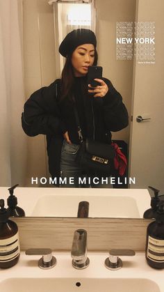 a woman taking a selfie in front of a bathroom mirror with the caption home michel