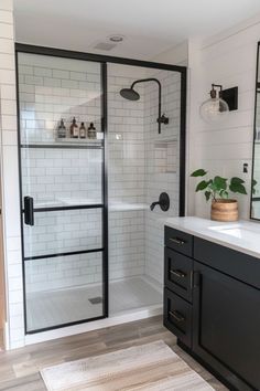 a bathroom with black cabinets and white tile on the walls, along with a large shower