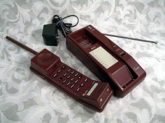 two old style phones sitting on top of a bed