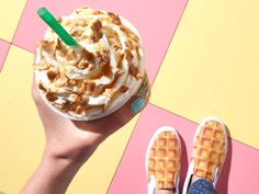 a person holding up a cup of ice cream with waffles on the side