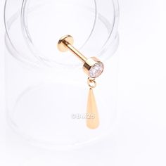 a gold nose ring with a dangling navel bar in the middle and a small diamond on top