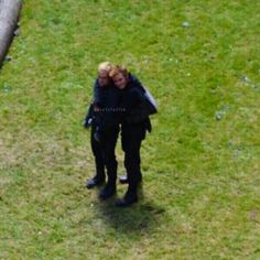 two people are standing in the grass with their arms around each other