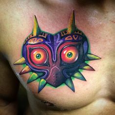 a chest tattoo with an image of a mask on it