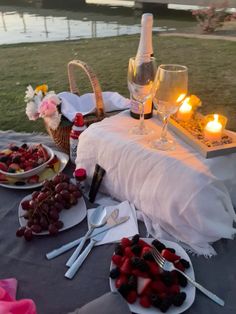 a table topped with plates of fruit next to a bottle of wine and two glasses