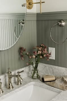 a bathroom sink sitting under a mirror next to a faucet mounted on a wall