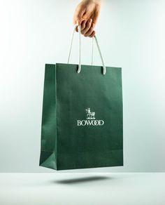 a person's hand holding a green bag with the words bowwood on it