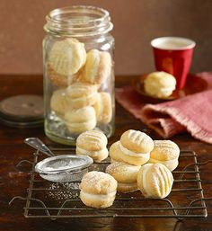 some cookies are sitting on a cooling rack next to a glass jar with powdered sugar