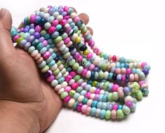 a hand holding several multicolored beads