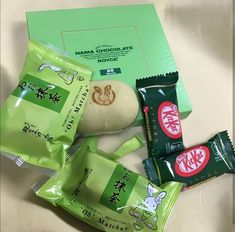 an assortment of snacks including cookies, candy and crackers sitting on a bed next to a green envelope