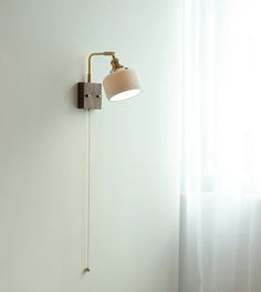 a white wall with a light on it and a lamp attached to the wall next to it