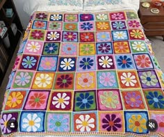 a crocheted granny blanket with flowers on the top and bottom is made in multi - colored squares