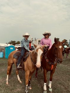 two people sitting on horses in a field