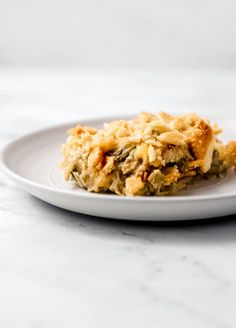 a white plate topped with food on top of a marble countertop next to a fork