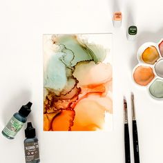 an art work with paints, brushes and watercolors on a white table top