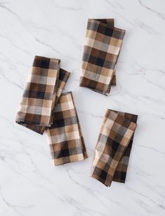 four brown and black checkered napkins on a marble surface