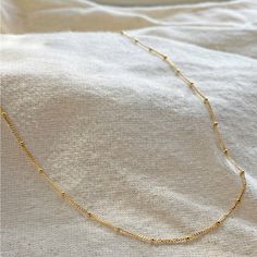 A delicate statement all on its own, the Satellite Chain Necklace features solid gold orbs accented along a dainty diamond cut curb chain for extra sparkle. This is everyday luxury at its finest. The 16.5" length sits right on the décolletage, to match any neckline and adds texture to a layered stack. View this style in white gold. Details: 9k Solid Gold diamond cut curb and ball chain Solid gold parrot clasp closure Chain measures 1mm wide 1.4mm solid balls Available in 42cm length (~16.5") Ple Classic Ball Chain Necklace As Gift, Delicate Gold Jewelry With Curb Chain, Elegant Beaded Link Chain Necklace, Elegant Beaded Chain Link Necklace, Classic Yellow Gold Beaded Chain Necklace, Classic Gold Ball Chain Necklace, Classic 14k Gold Ball Chain Necklaces, Classic Satellite Chain Necklace, Minimalist Yellow Gold Ball Chain Necklace