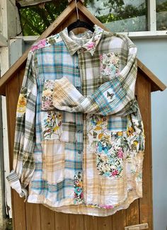 a shirt hanging on a clothes hanger in front of a wooden door with flowers