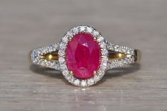 an oval shaped ruby and diamond ring on a wooden surface