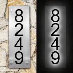 two metal signs with numbers on them sitting next to each other in front of a stone wall