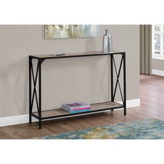 a black metal and glass console table with books on it's shelf next to a rug