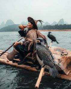 a man sitting on top of a wooden boat with two birds perched next to him