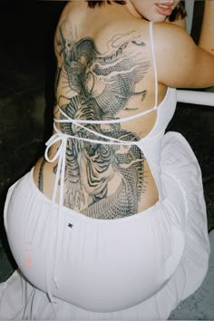 a woman with tattoos on her back sitting down