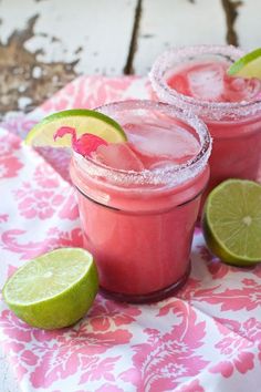 two margaritas with lime slices on the rim and one has a pink drink in it