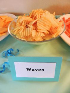 there is a bowl of chips on the table next to other plates with food in it