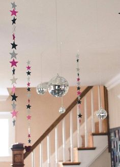 stars and disco balls hanging from the ceiling in front of stairs with chandelier