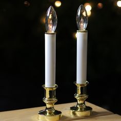 two white candles sitting on top of a wooden table