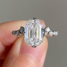 a person holding an engagement ring with a large diamond in it's middle finger