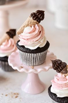 three cupcakes with pink frosting and chocolate sprinkles on top