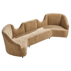 a curved couch with sheepskin on the back and legs, sitting in front of a white background