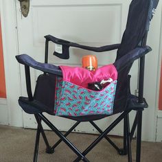 a black folding chair with a pink and blue bag on it's back, sitting in front of a door